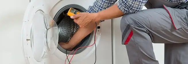 Dryer repair technician inspecting and repairing a clothes dryer in Orange, CA