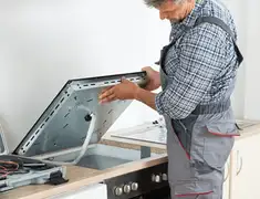 Appliance repair technician installing a built-in cooktop in Orange, CA