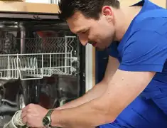 Dishwasher repair technician inspecting and servicing an open dishwasher in Orange, CA