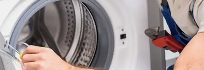 Appliance technician repairing a clothes dryer drum and internal parts in Orange, CA