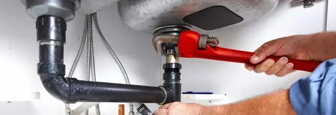 Garbage disposal repair technician tightening the sink drain and disposal connection in Orange, CA