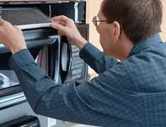 Appliance repair technician replacing a microwave vent filter in Orange, CA