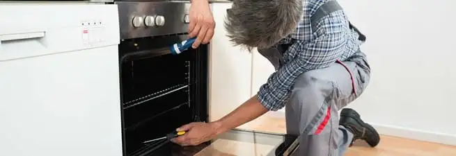 Oven repair technician inspecting and servicing an electric oven in Orange, CA