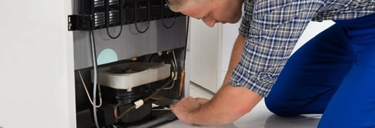 Refrigerator repair technician servicing the compressor and condenser area in Orange, CA