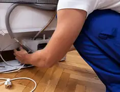 Appliance repair technician fixing refrigerator water line and connections in Orange, CA