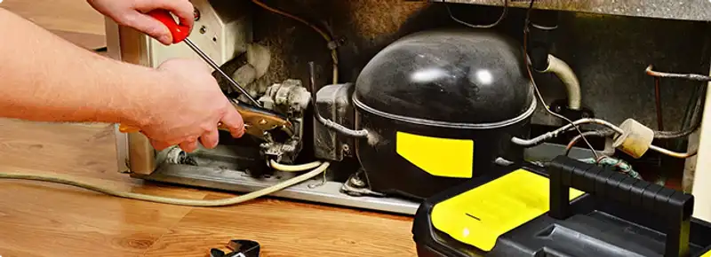 Refrigerator repair technician fixing the compressor and wiring in Orange, CA