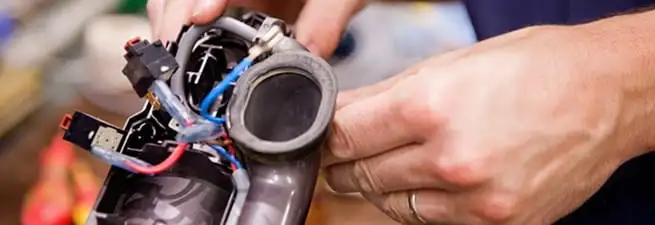 Vacuum repair technician reconnecting wiring and components in Orange, CA