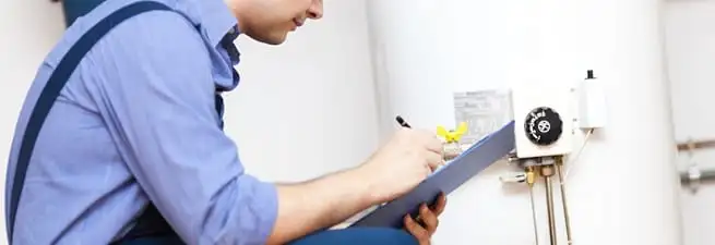 Water heater repair technician inspecting the unit and recording service notes in Orange, CA