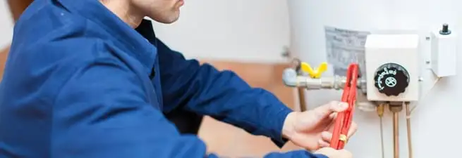 Water heater repair technician adjusting the temperature control and gas valve in Orange, CA